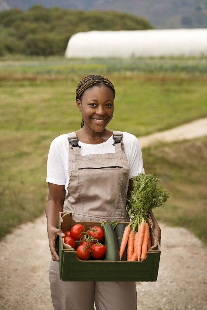 Femme souriante tenant des légumes frais récoltés à la ferme