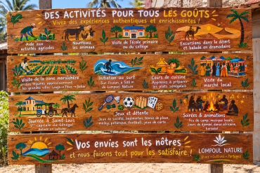 Panneau des activités de Lompoul Nature : ferme, surf, dromadaire, cuisine, marché, Saint-Louis, feu de camp